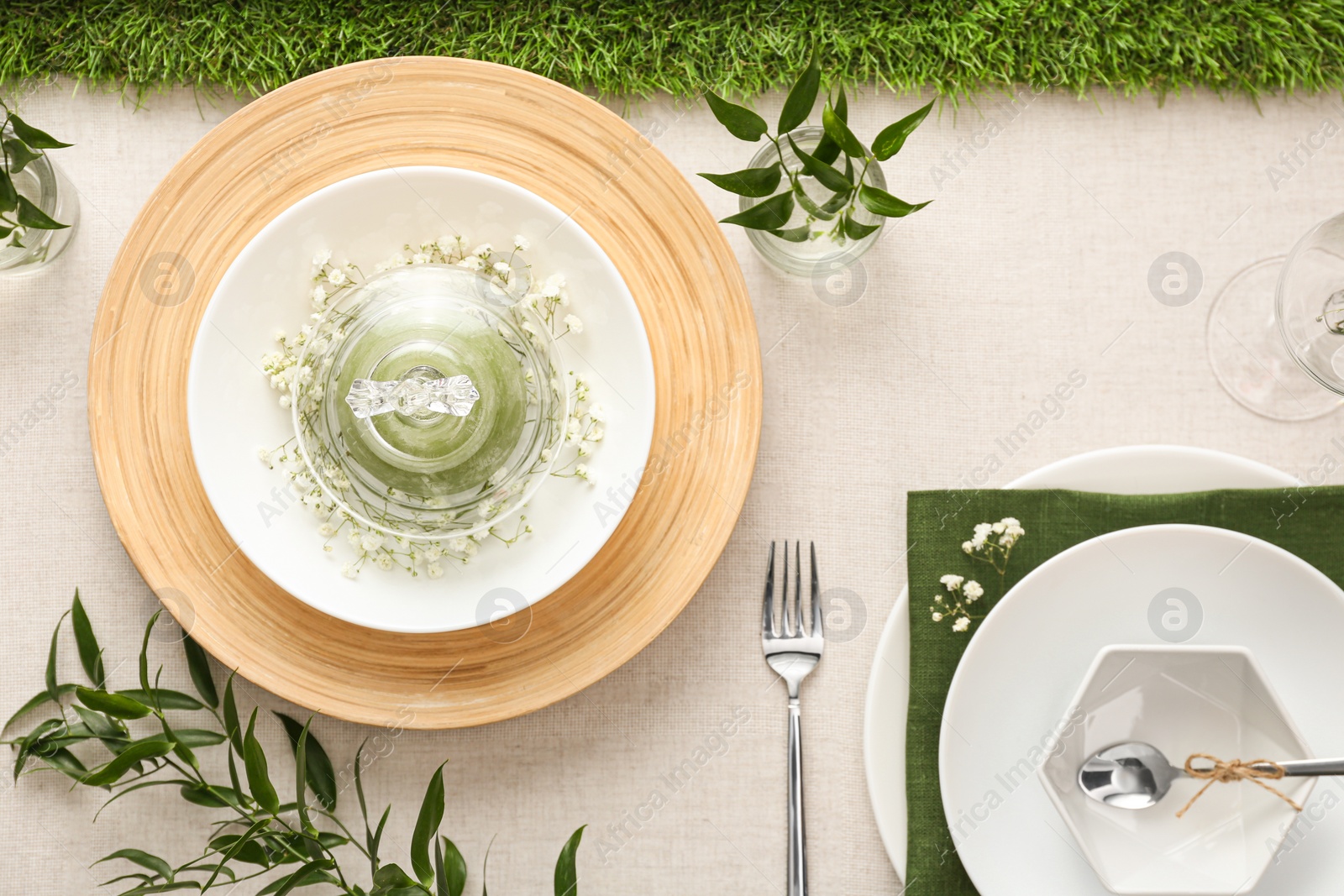 Photo of Elegant table setting with green plants on light cloth, flat lay