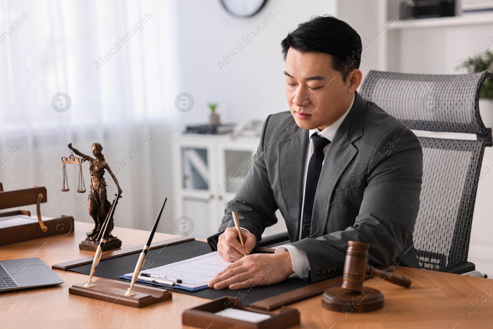 Photo of Notary writing notes at wooden table in office