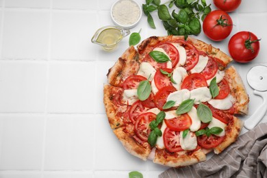 Photo of Delicious Caprese pizza with tomatoes, mozzarella and basil served on white tiled table, flat lay. Space for text