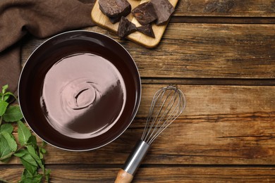 Delicious chocolate cream, whisk and mint on wooden table, flat lay. Space for text