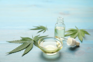 Photo of Hemp leaves and CBD oil or THC tincture on light blue wooden table