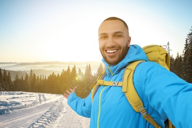 Image of Smiling young man taking selfie in snowy mountains