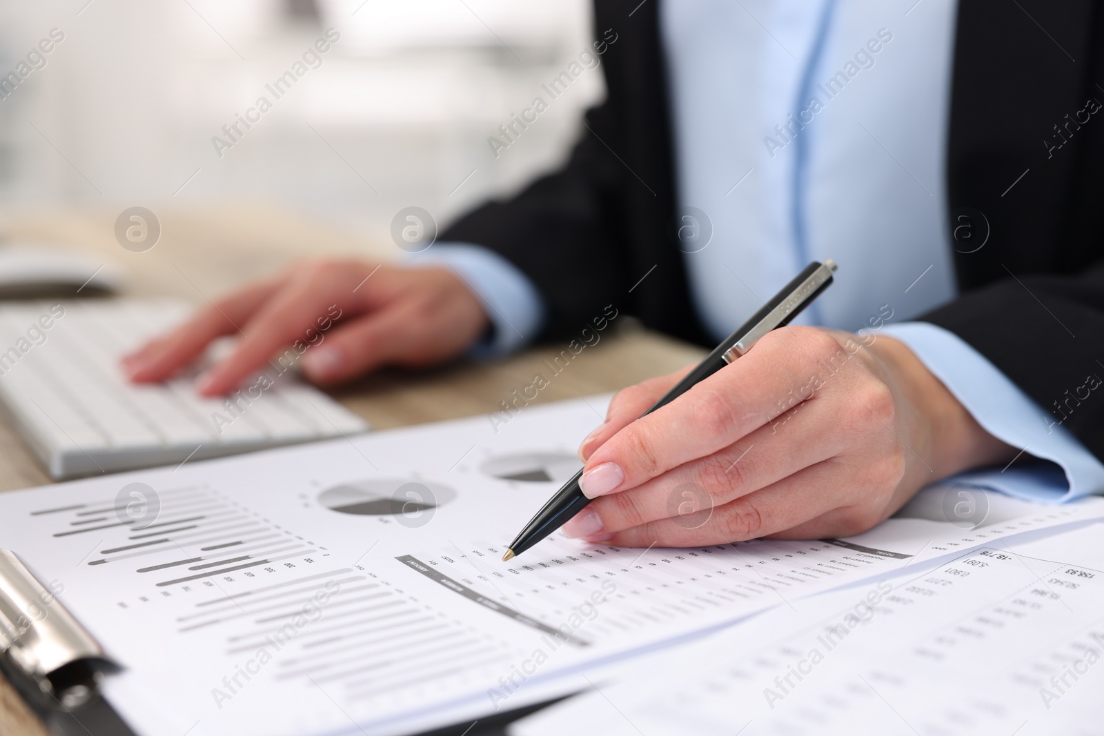 Photo of Secretary doing paperwork at table in office, closeup