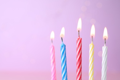 Photo of Burning birthday cake candles on color background. Space for text