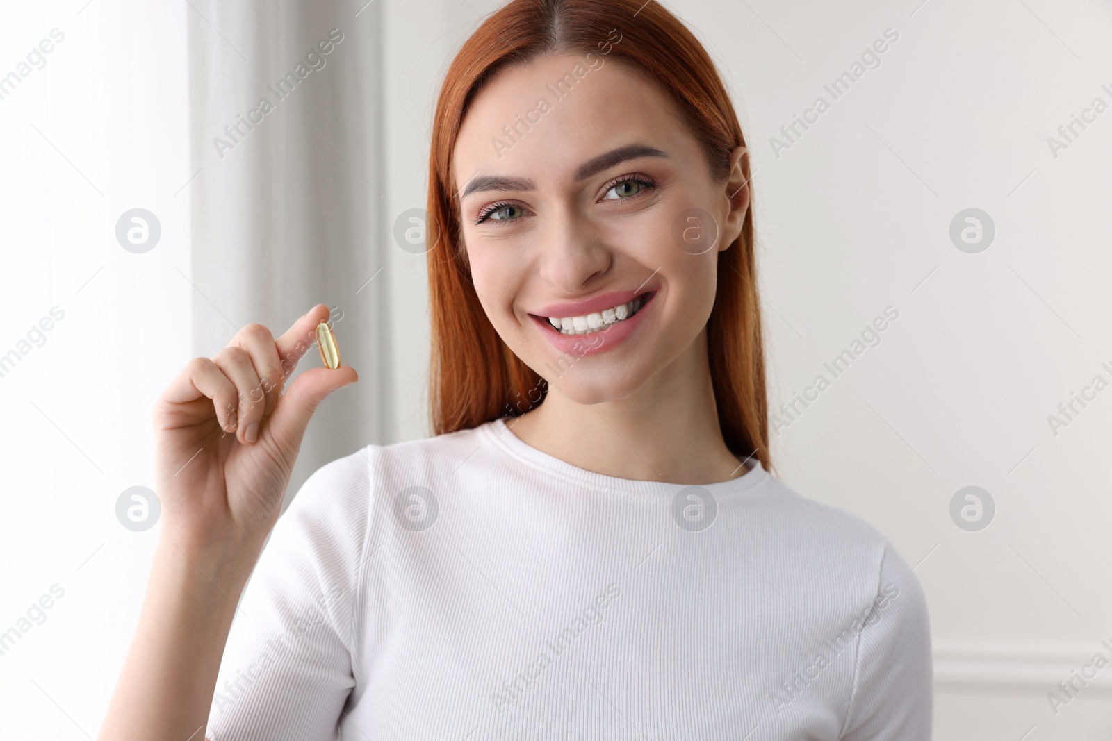 Photo of Beautiful young woman with vitamin pill at home