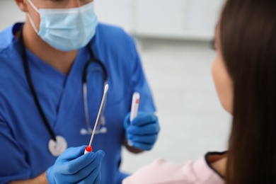 Doctor taking sample for DNA test from woman in clinic