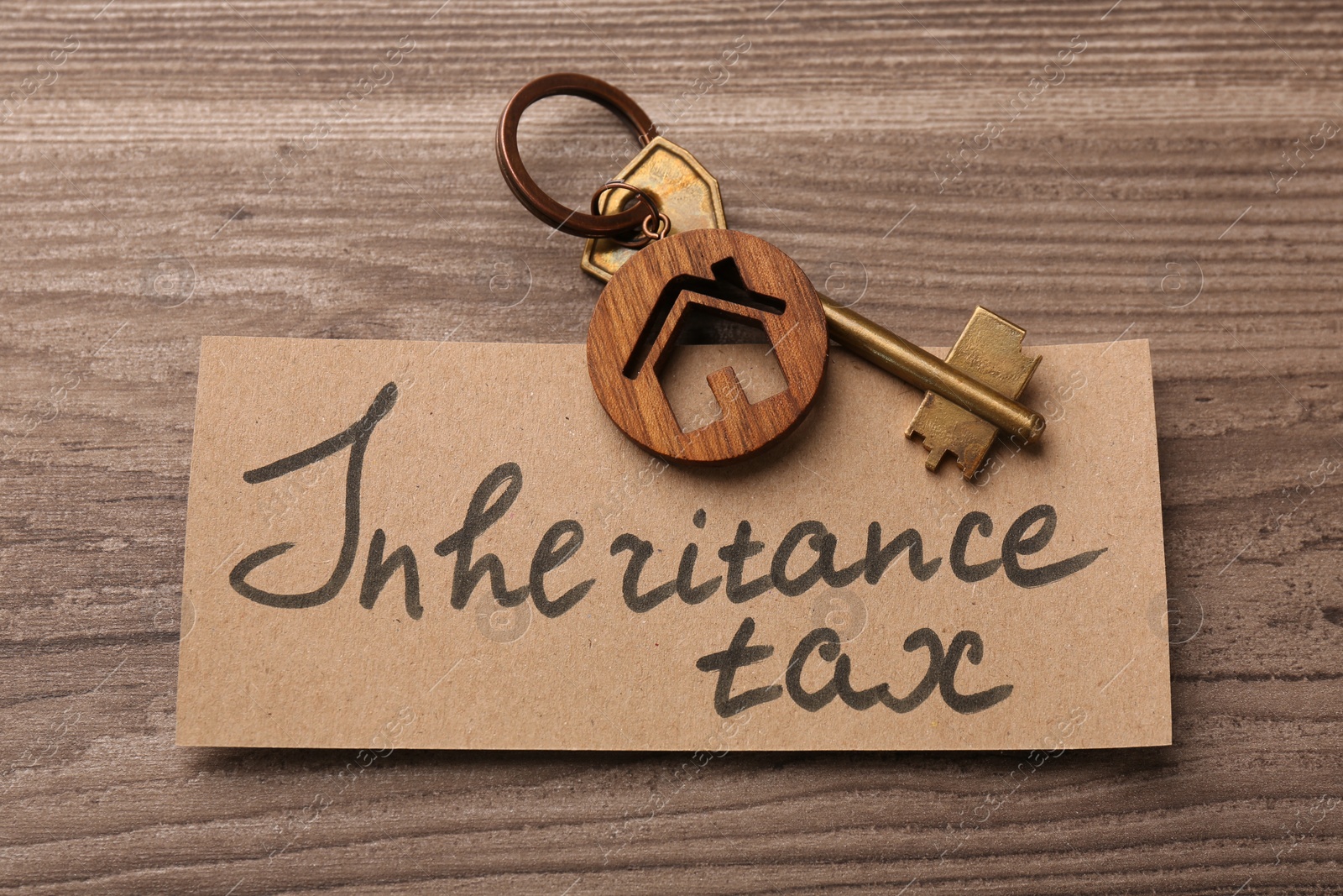 Photo of Inheritance Tax. Card and key with key chain in shape of house on wooden table, top view