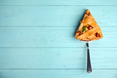 Photo of Slice of delicious fresh peach pie on light blue wooden table, top view. Space for text