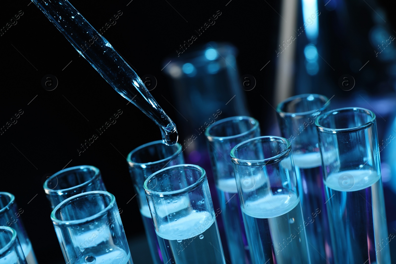 Photo of Dripping reagent into test tube on black background, closeup. Laboratory analysis