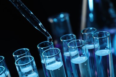 Photo of Dripping reagent into test tube on black background, closeup. Laboratory analysis