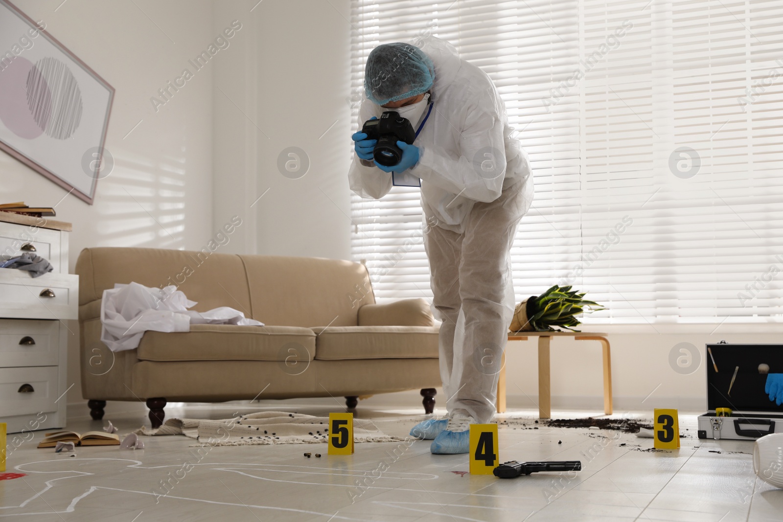 Photo of Investigator in protective suit making photo of crime scene indoors