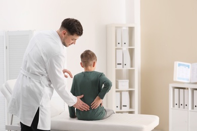 Photo of Chiropractor examining child with back pain in clinic