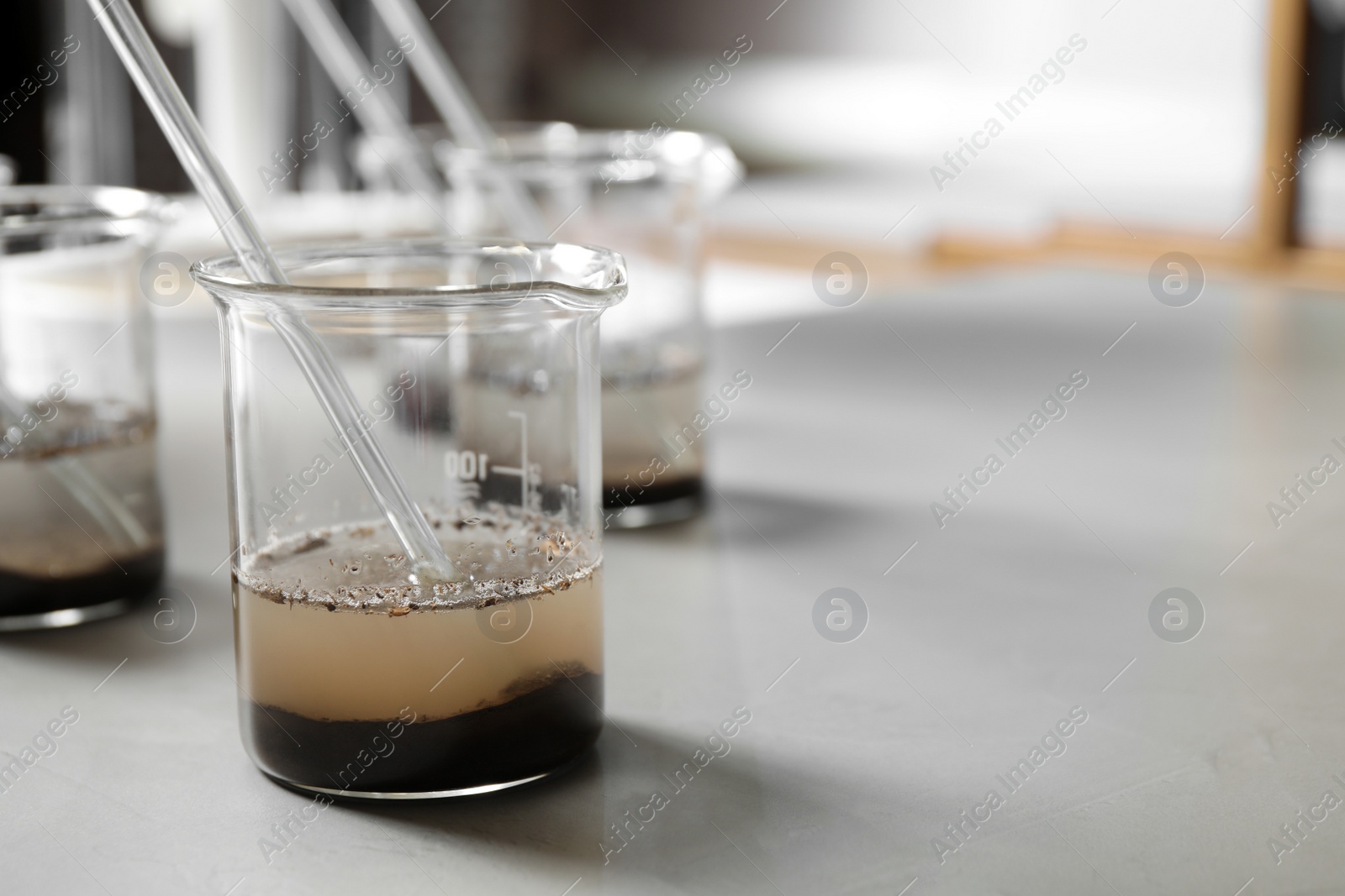 Photo of Beaker with soil extract on light table, space for text. Laboratory analysis