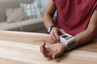 Photo of Man checking blood pressure at table indoors, closeup with space for text. Cardiology concept