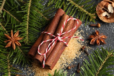 Photo of Different aromatic spices and fir branches on grey textured table, flat lay