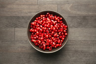 Photo of Tasty ripe pomegranate grains on dark wooden table, top view