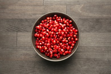 Tasty ripe pomegranate grains on dark wooden table, top view