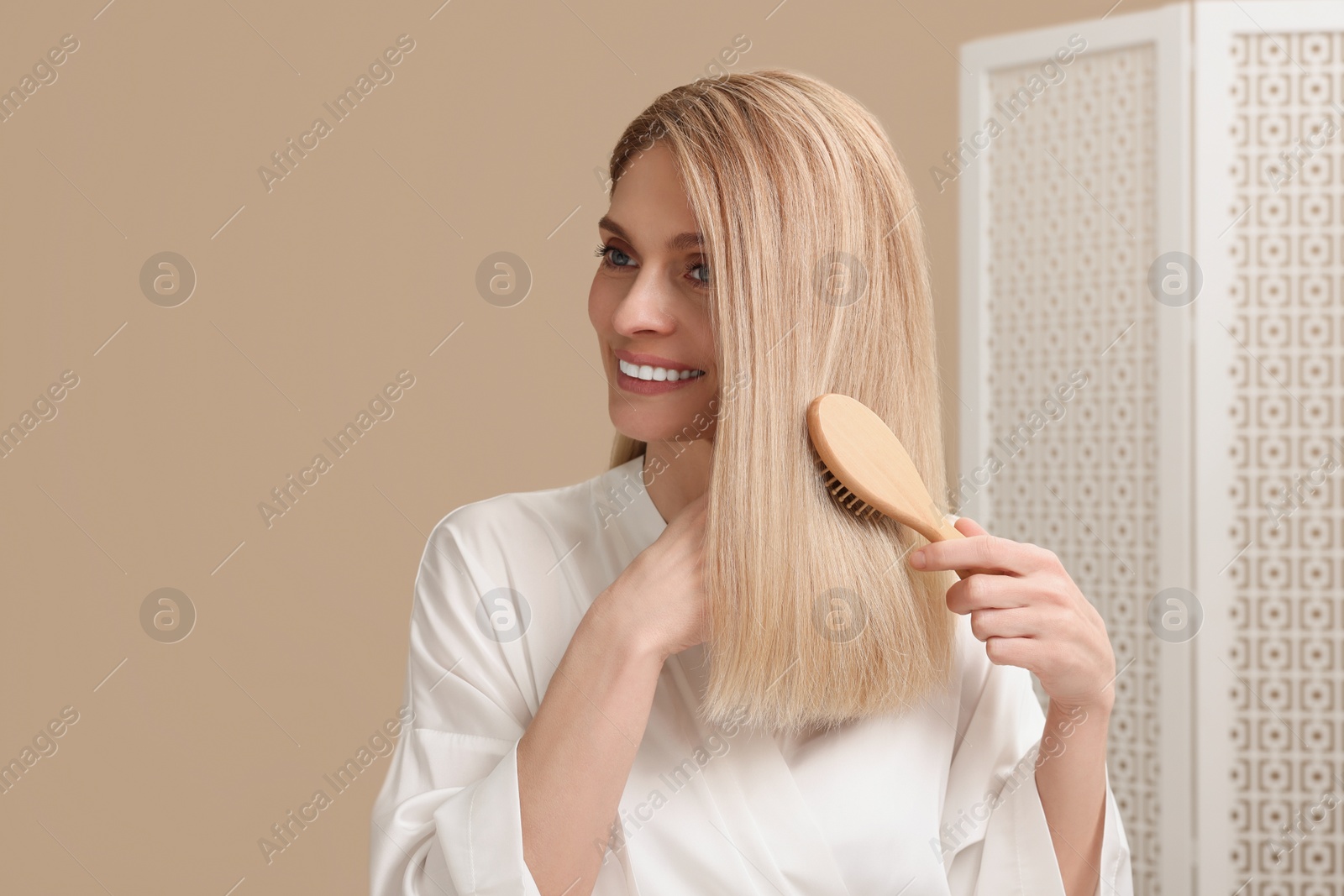 Photo of Beautiful woman brushing her hair in bathroom