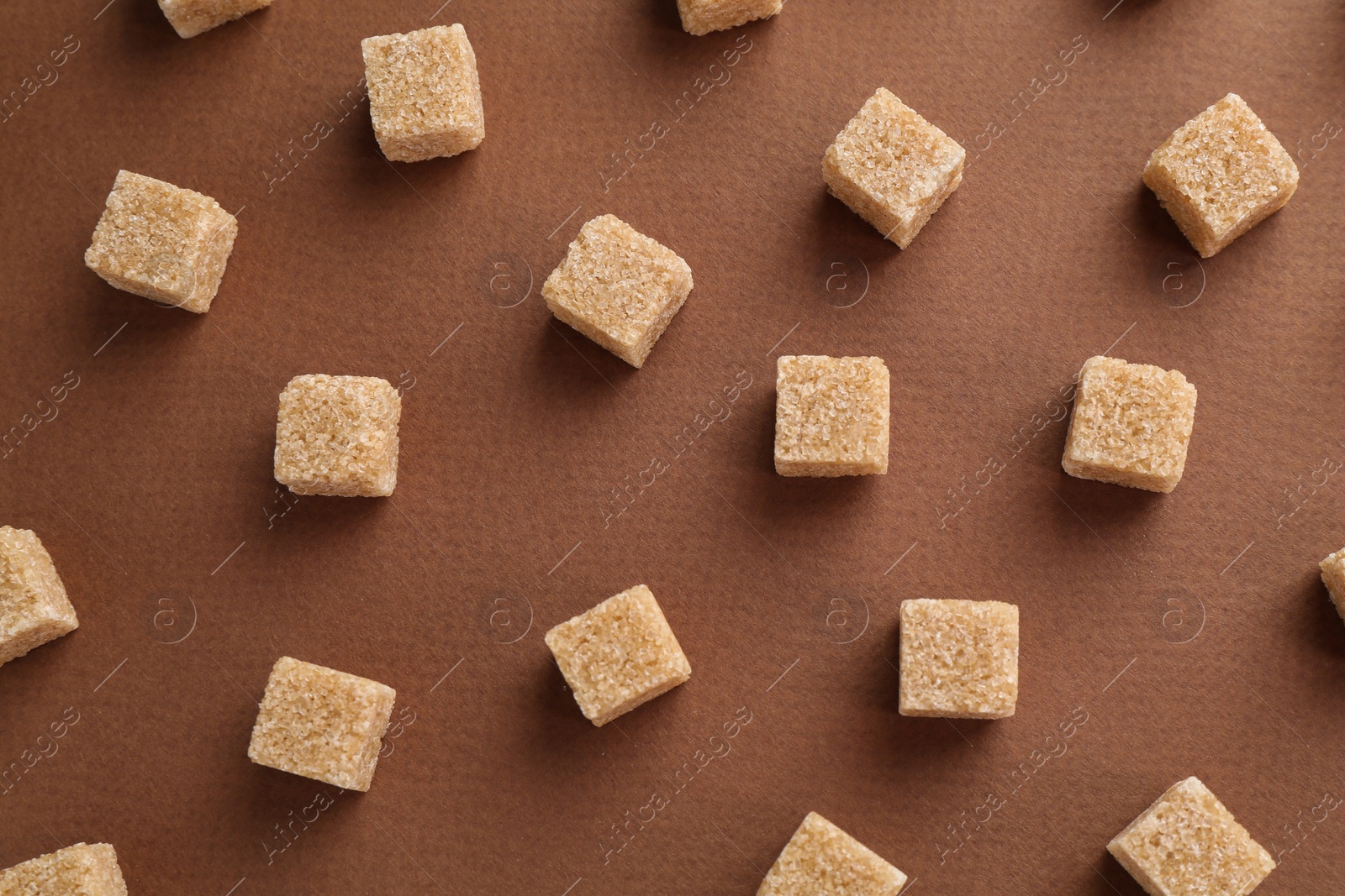 Photo of Brown sugar cubes on color background, top view