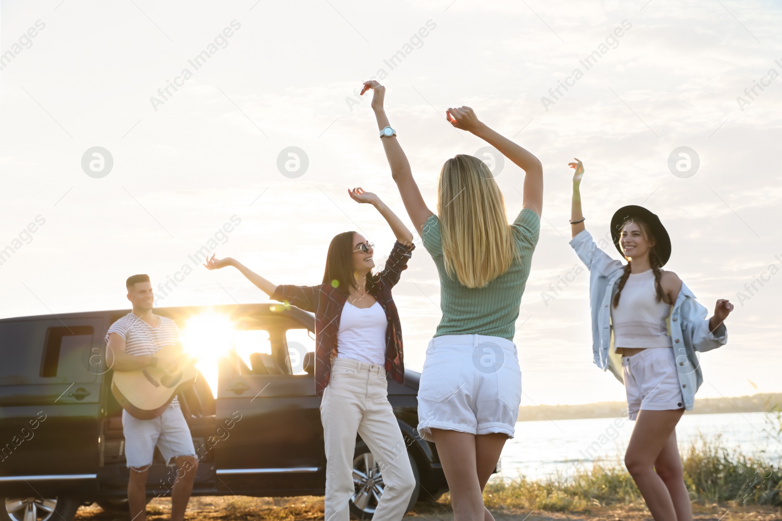 Photo of Happy friends having fun near car outdoors. Summer trip