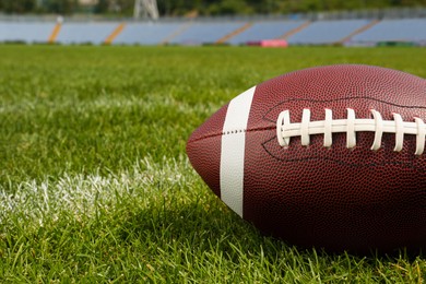 Photo of American football ball on green field grass in stadium, closeup