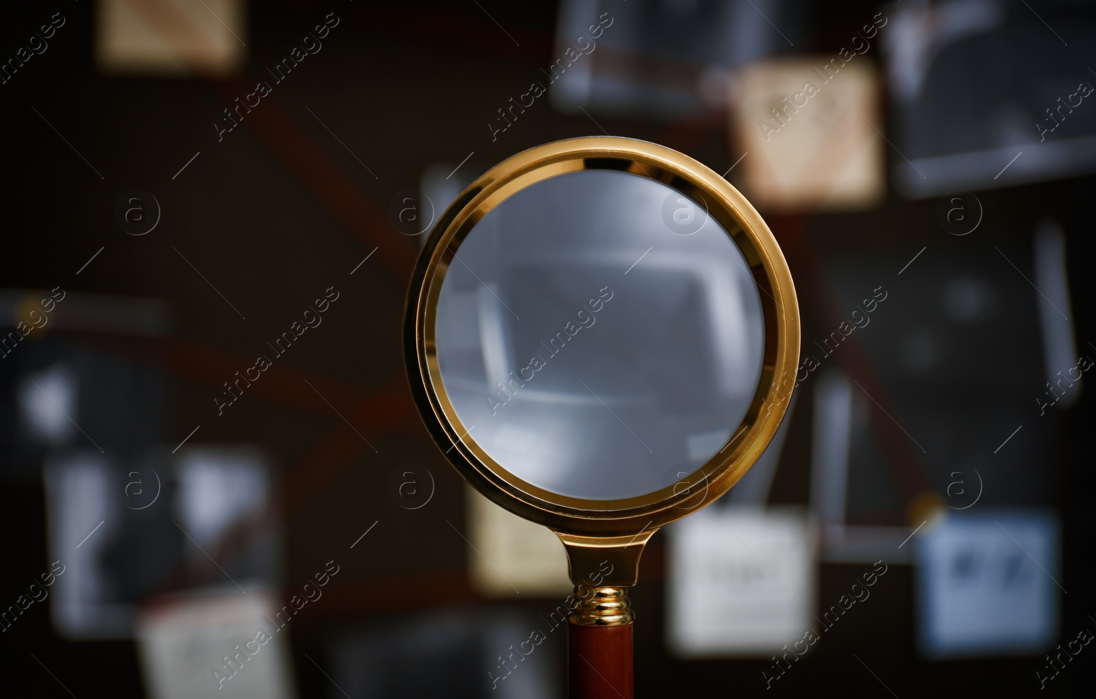 Photo of Looking at detective board through magnifying glass, closeup