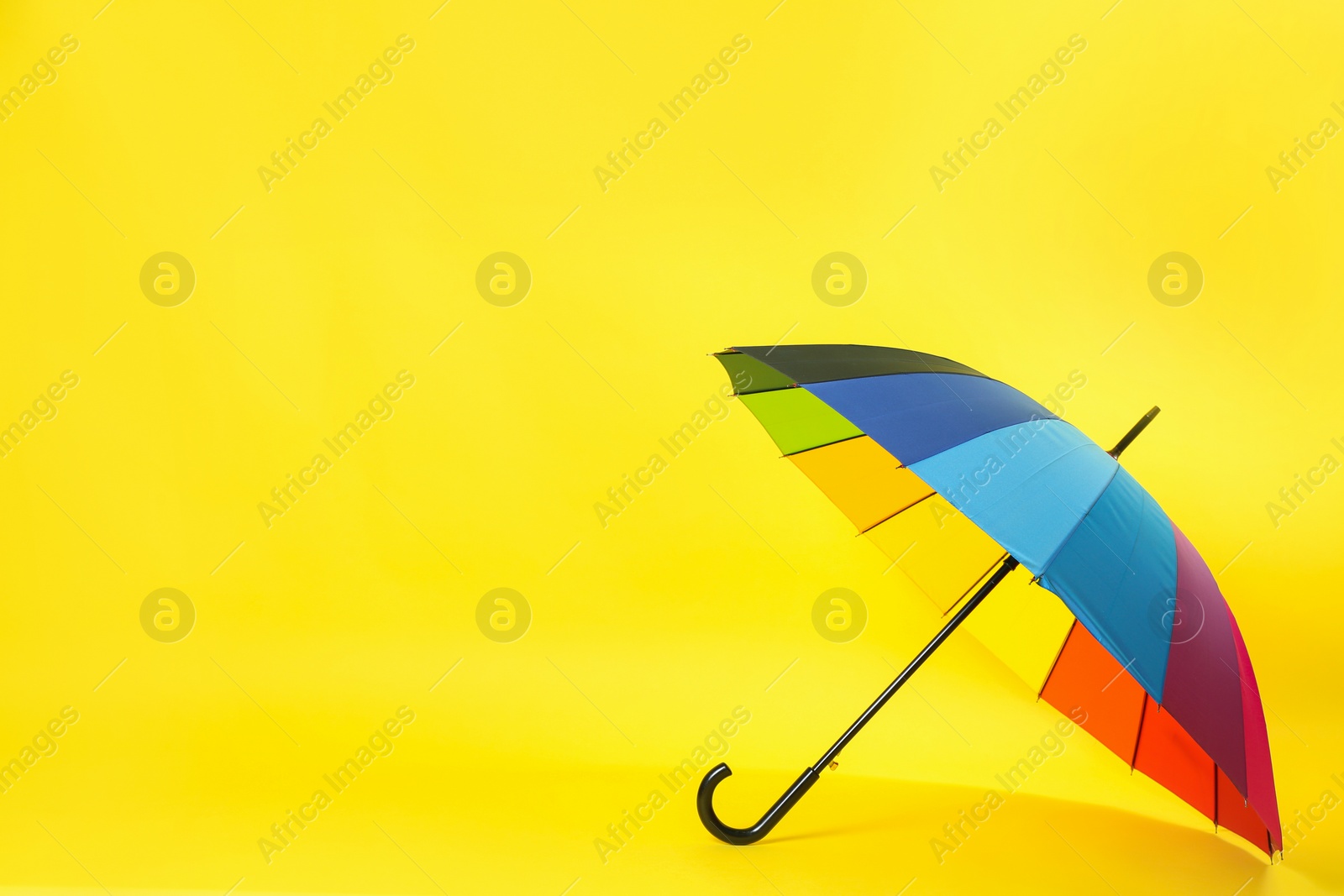 Photo of Colorful umbrella on light yellow background. Space for text