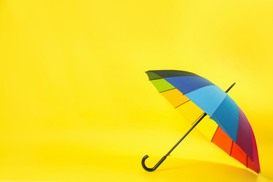 Colorful umbrella on light yellow background. Space for text