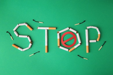 Photo of Word Stop made of broken cigarettes, prohibition sign and burnt matches on green background, flat lay. Stop smoking concept