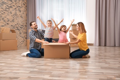 Happy family playing with cardboard box in their new house. Moving day
