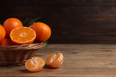 Delicious tangerines with leaves on wooden table. Space for text