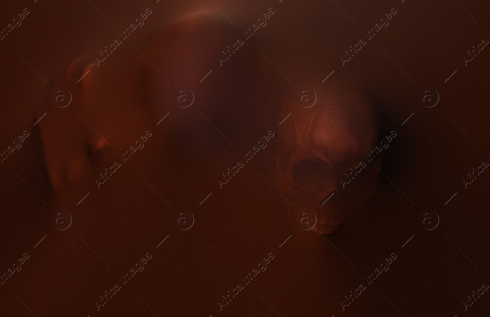 Photo of Silhouette of creepy ghost with skulls behind brown cloth