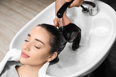 Stylist washing client's hair at sink in beauty salon