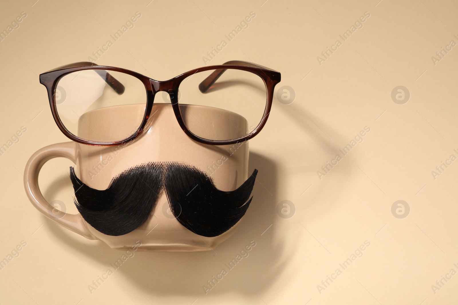 Photo of Artificial moustache, cup and glasses on beige background, top view. Space for text