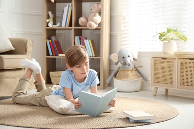 Little boy reading book on floor at home