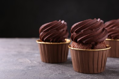 Photo of Delicious chocolate cupcakes on grey textured table, closeup. Space for text
