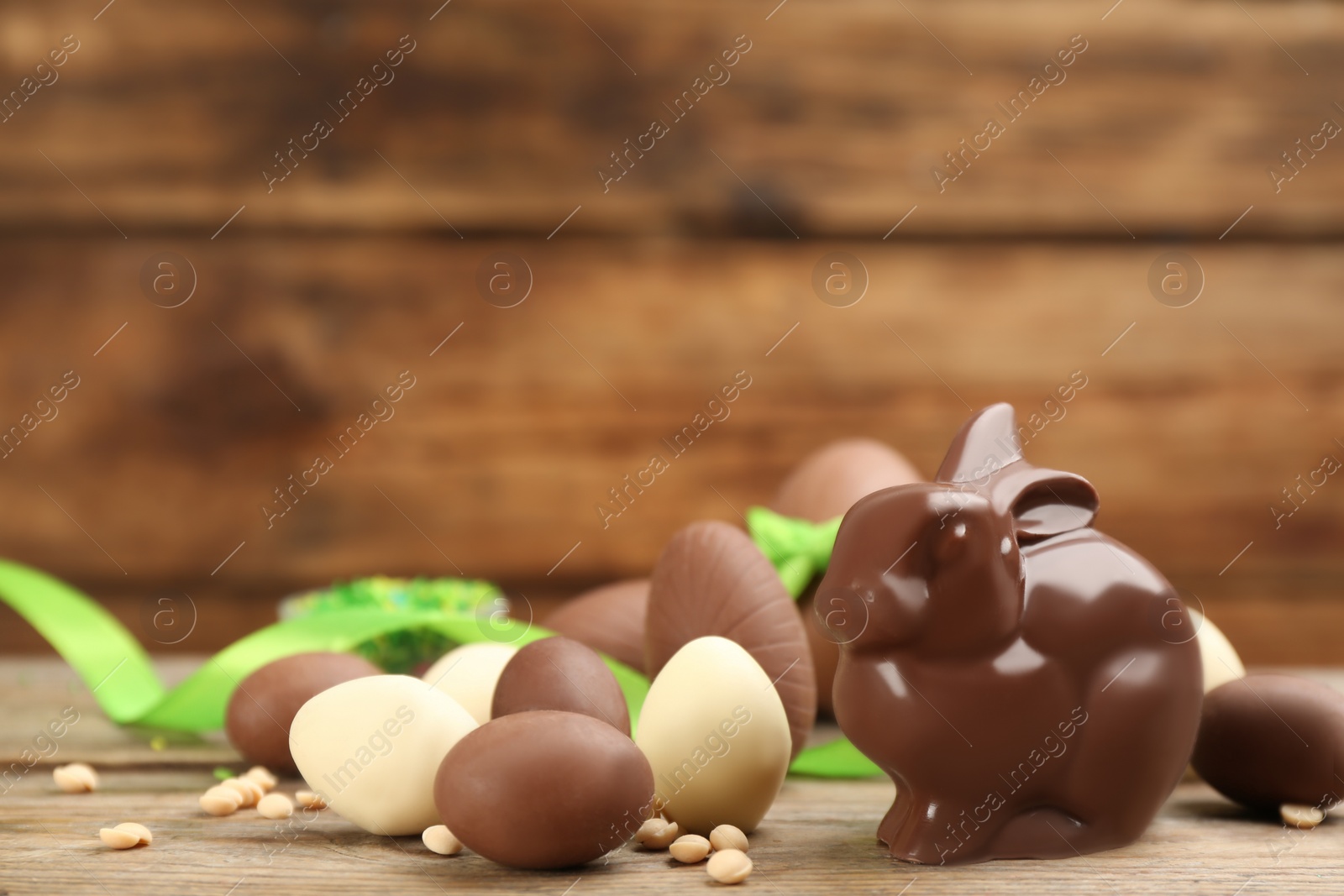 Photo of Chocolate Easter bunny and eggs on wooden table. Space for text