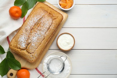 Photo of Delicious homemade yogurt cake with powdered sugar and tangerines on white wooden table, flat lay. Space for text