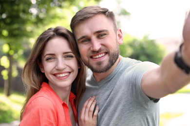 Happy young couple taking selfie in park