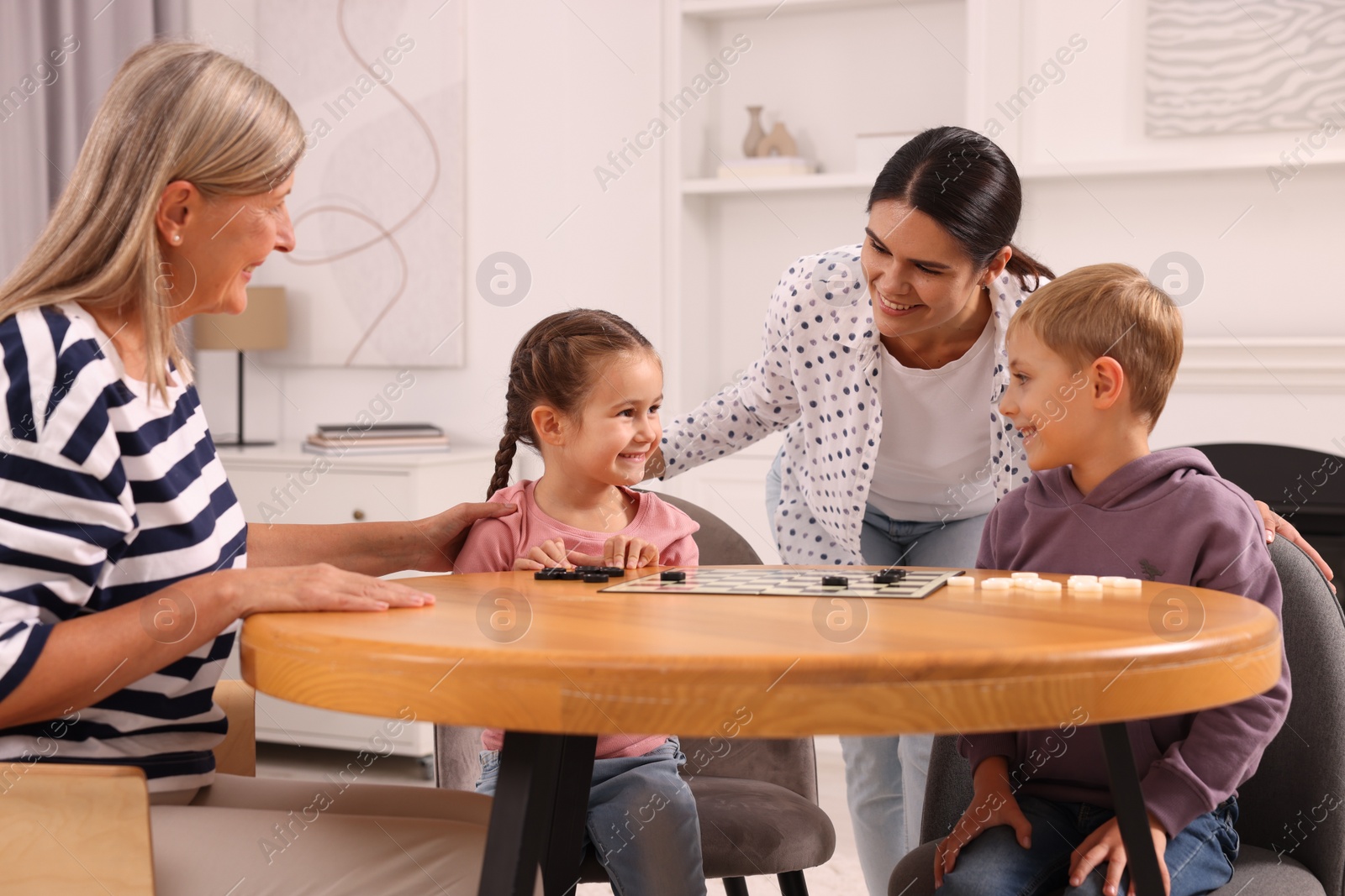 Photo of Family playing checkers at wooden table in room