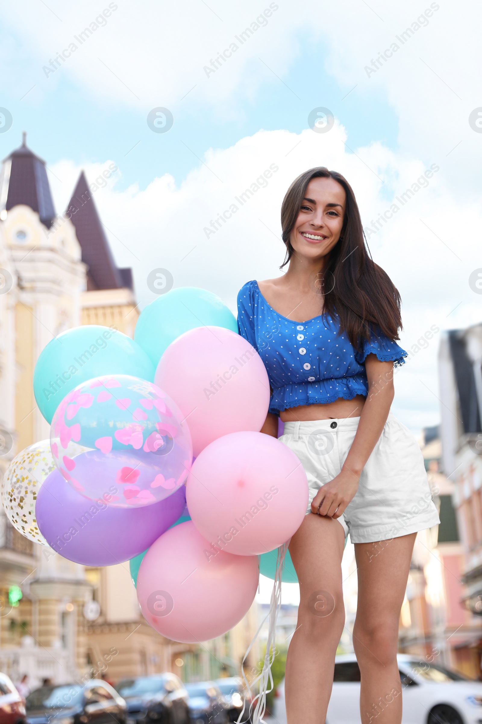 Photo of Beautiful young woman with color balloons on city street