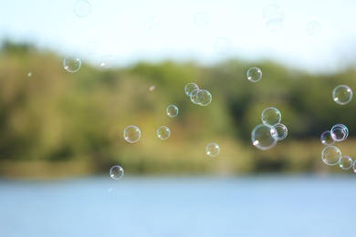 Photo of Beautiful translucent soap bubbles outdoors on sunny day