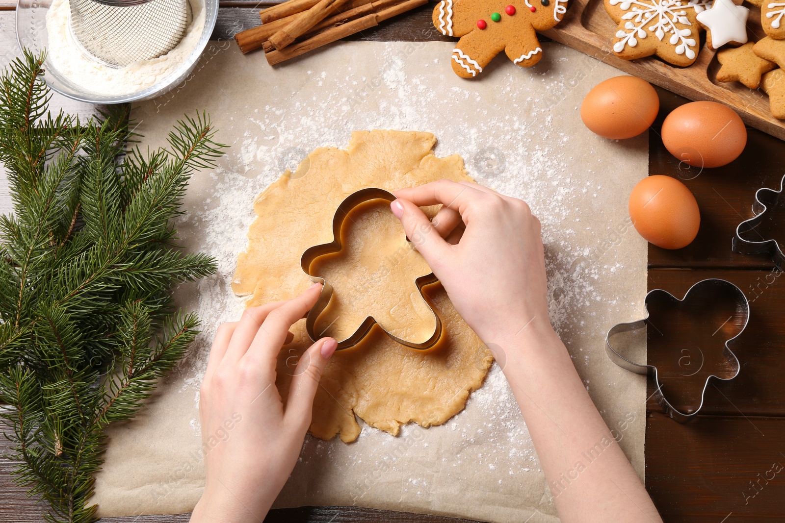 Photo of Woman making Christmas cookies with cutters at wooden table, top view