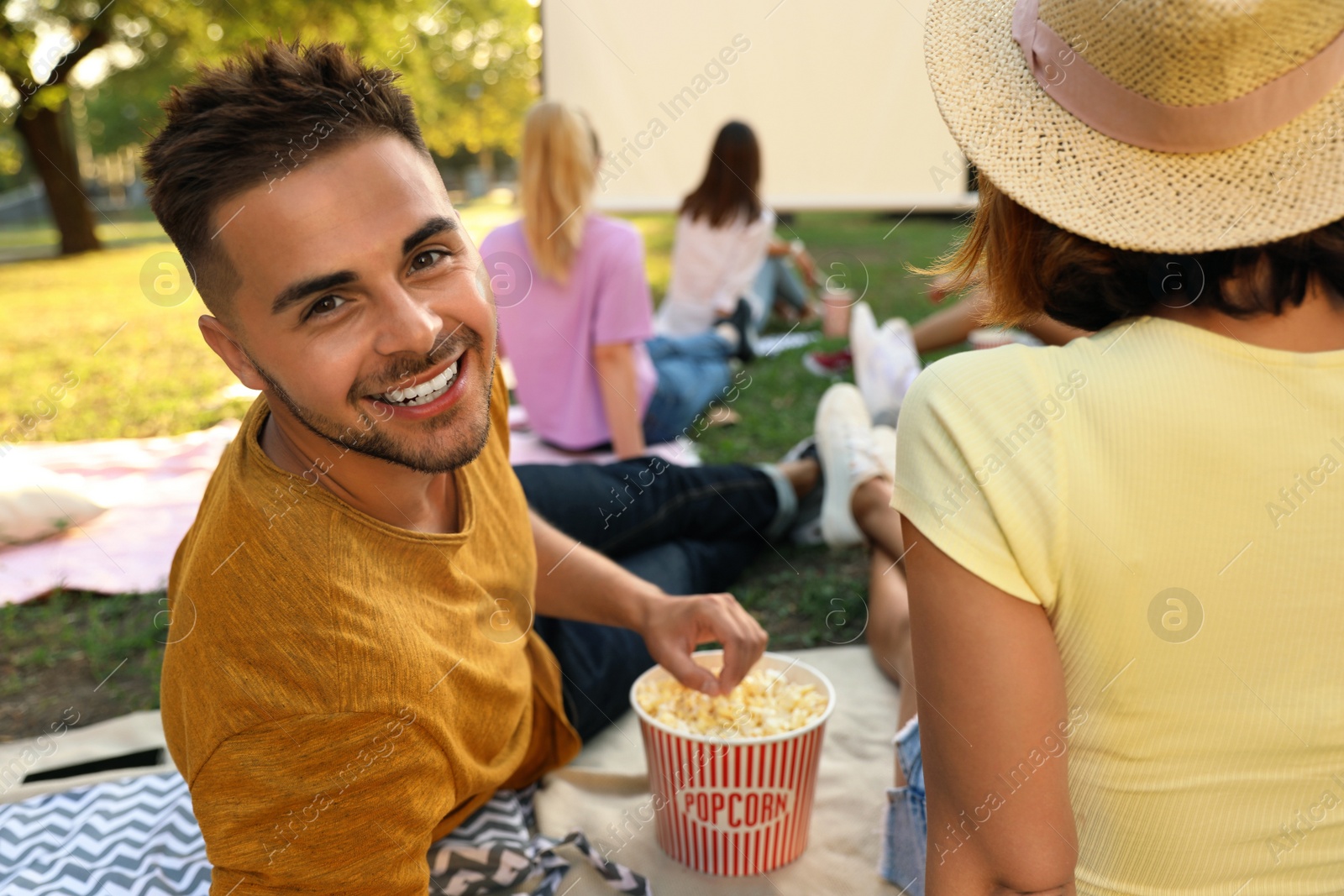 Photo of Young couple with popcorn watching movie in open air cinema. Space for text