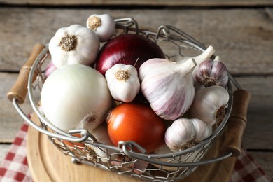 Photo of Fresh raw garlic and onions in metal basket on table, closeup