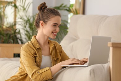 Photo of Happy young woman with laptop in living room