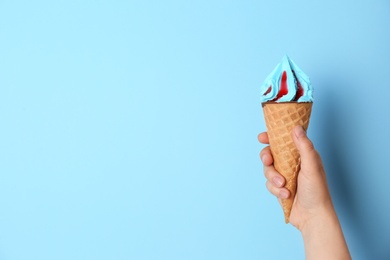 Photo of Woman holding waffle cone with delicious ice cream on color background. Space for text