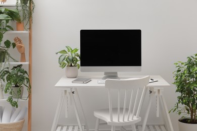 Spacious workspace with desk, chair, computer and potted plants at home