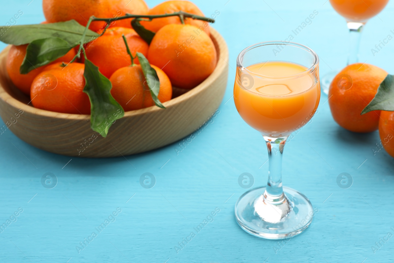 Photo of Delicious tangerine liqueur and fresh fruits on light blue wooden table