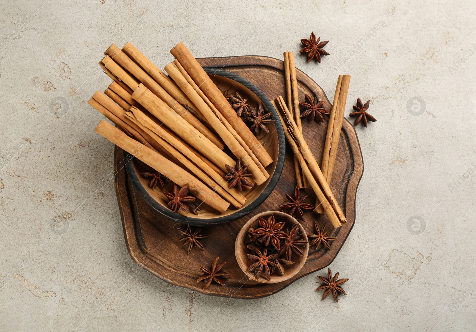 Photo of Aromatic cinnamon sticks and anise on light grey table, flat lay